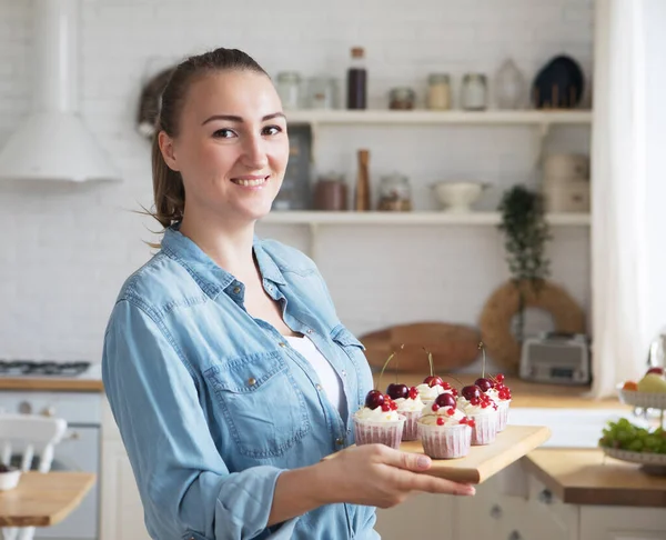 Életmód, élelmiszer, emberek és a kisvállalkozás koncepciója: fiatal pék nő gazdaság cupcakes. — Stock Fotó