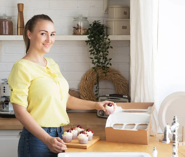 Konyha, hobbik, emberek és főzés koncepció.Fiatal nő cukrász tesz mályvacukrot egy dobozban. Kisvállalkozások. — Stock Fotó