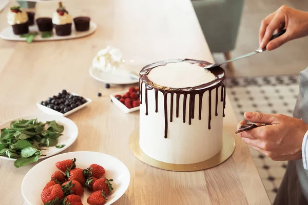 Повар-кондитер на кухне украшает торт шоколадом — стоковое фото