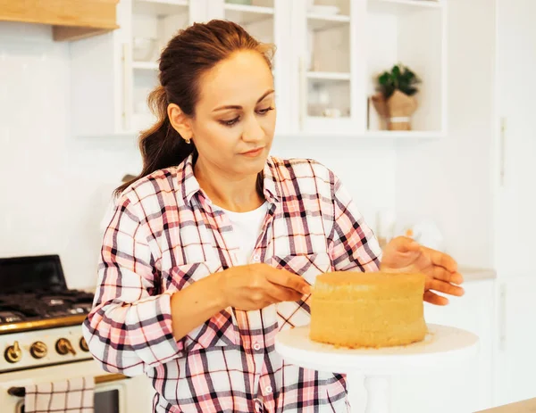 Young woman cuts cake cakes with a knife — Stock Photo, Image