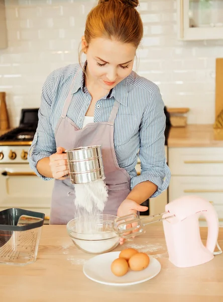 Young woman pastry chef sifters flour for cake flush. Delicious pastries. Hobby. Small home business. — Stock Photo, Image