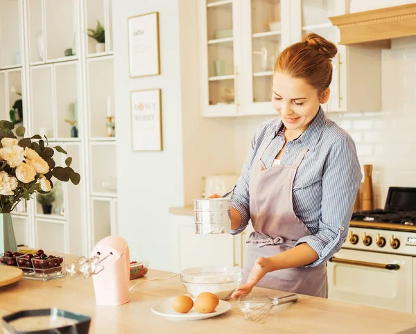 Young woman pastry chef sifters flour for cake flush. Delicious pastries. Hobby. Small home business. — Stock Photo, Image