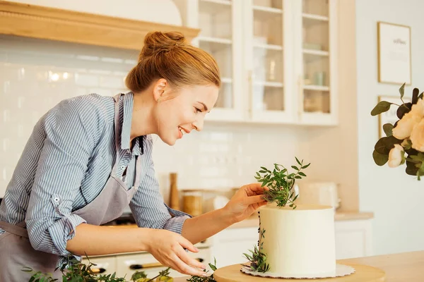 Giovane pasticciera donna lavora con le erbe per decorare la torta. Deliziosi dolci. Hobby. Piccola impresa domestica. — Foto Stock