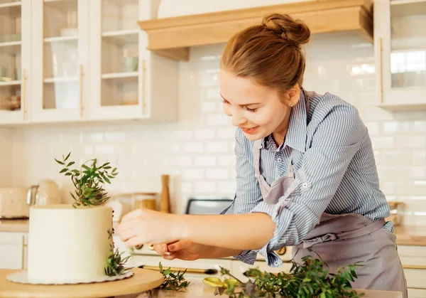 Young woman pastry chef works with herbs to decorate the cake. Delicious pastries. Hobby. Small home business. — Stock Photo, Image