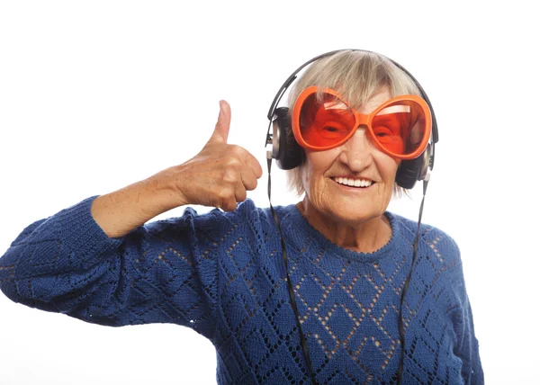 Müzik dinleyen ve baş parmağını kaldıran komik yaşlı kadın..