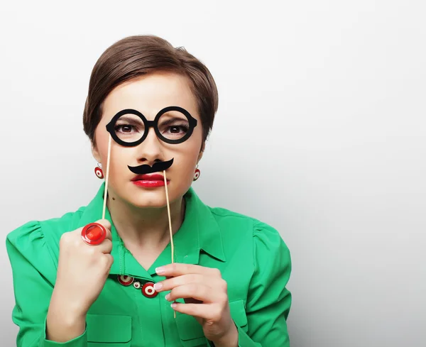 Young woman holding mustache and glasses on a stick. — Stock Photo, Image