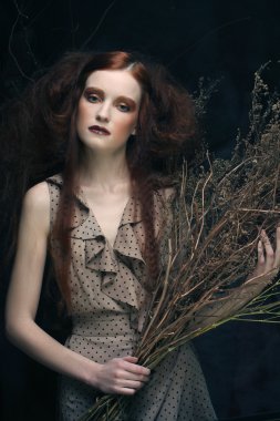 Kuru dallarla süslenmiş parlak bir kadın.