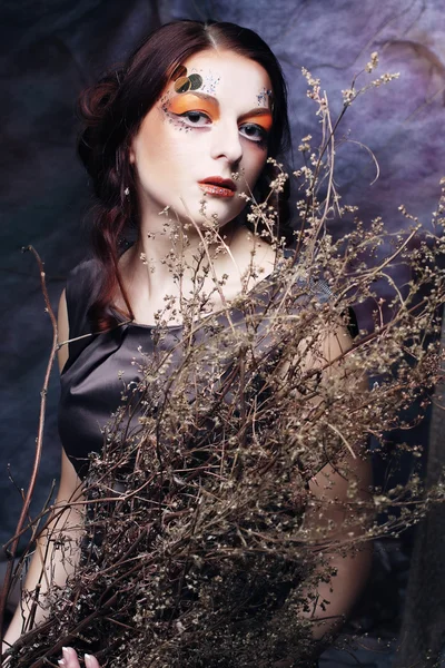 Mujer con maquillaje brillante con ramas secas — Foto de Stock