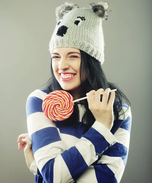 Mujer con sombrero de invierno celebración de piruleta grande — Foto de Stock