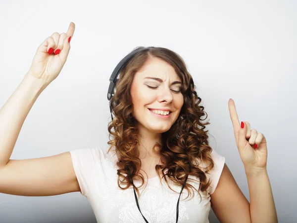 Młoda kręcona kobieta ze słuchawkami słuchająca muzyki. — Zdjęcie stockowe