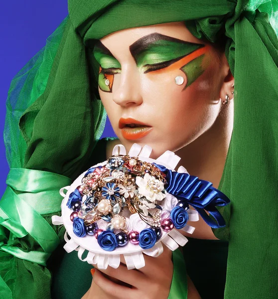 Femme avec maquillage créatif tenant un bouquet de bijoux — Photo