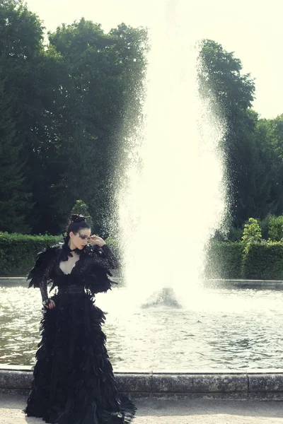 Fashion model posing next fountain in summer park