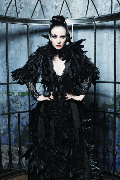 Fashion model in fantasy dress posing in steel cage. — Stock Photo, Image