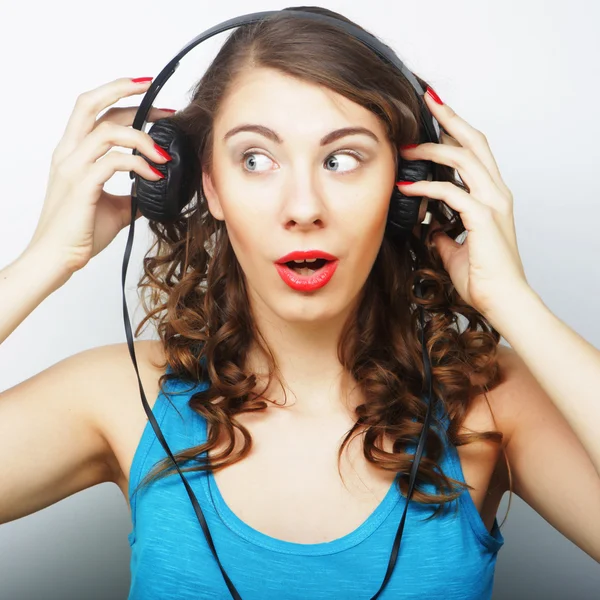Młoda kręcona kobieta ze słuchawkami słuchająca muzyki. — Zdjęcie stockowe