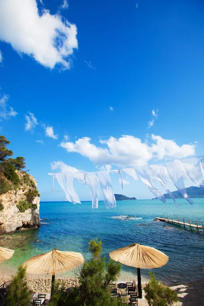 Ряд солом'яних парасольок і лаунжів на пляжі — стокове фото
