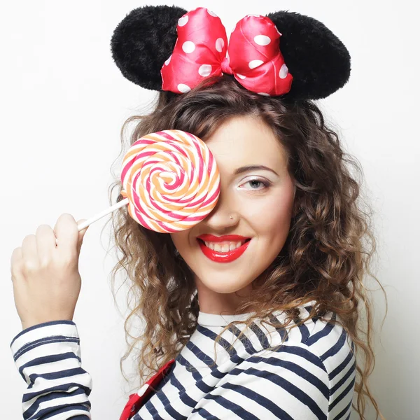 Joven rizado mujer con ratón orejas celebración piruleta — Foto de Stock