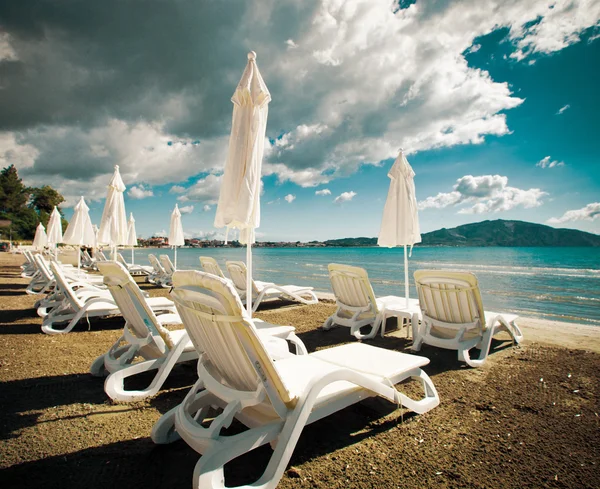 Liegestühle mit Sonnenschirmen am schönen Strand — Stockfoto