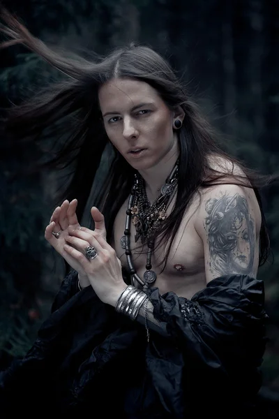 Young man with long hair in the dark forest — Stock Photo, Image