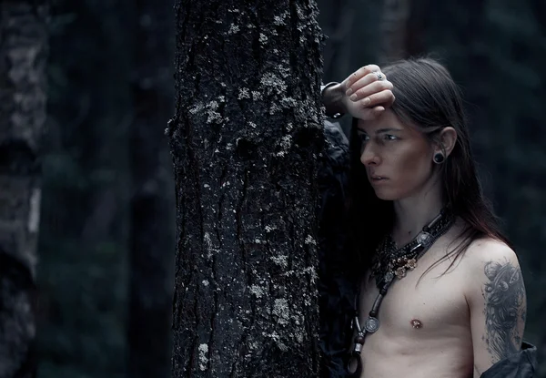 Молодий чоловік з довгим волоссям у темному лісі — стокове фото
