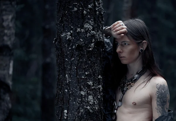 Jovem com cabelos longos na floresta escura — Fotografia de Stock