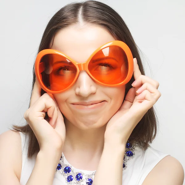 Jonge gelukkig vrouw met grote oranje zonnebril — Stockfoto