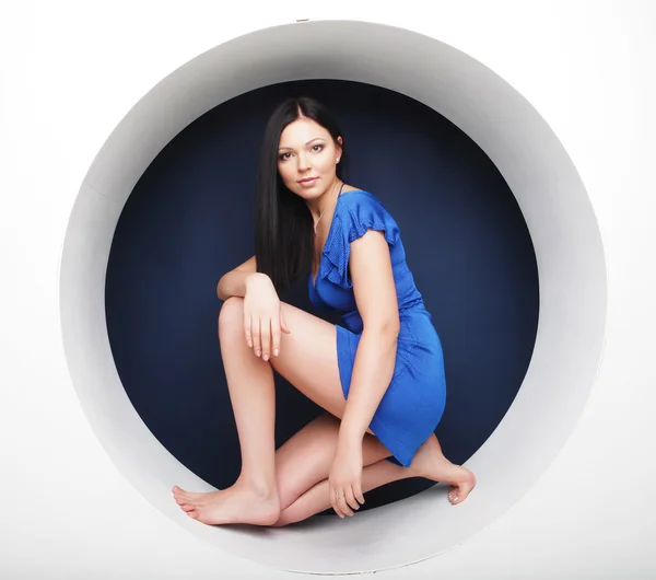 Brunette in blauwe jurk zitten in een cirkel — Stockfoto