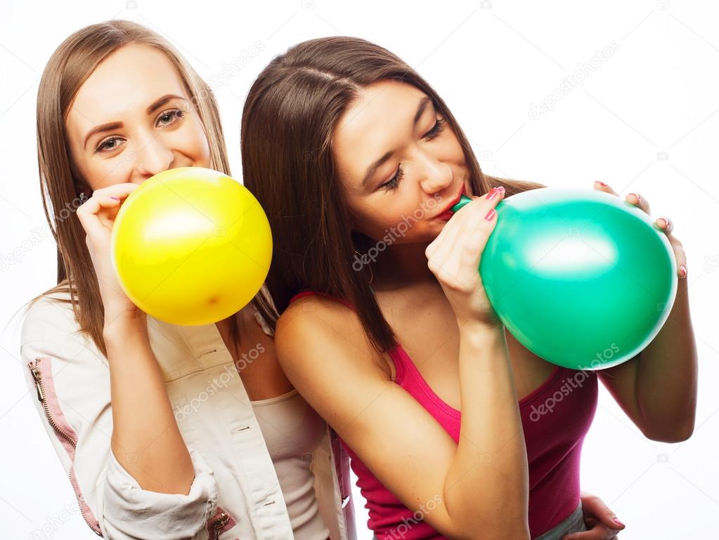 hipster girls smiling and holding colored balloons