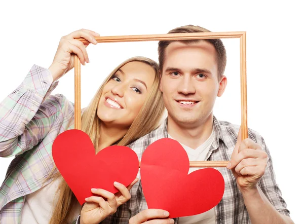 Encantador casal segurando quadro e corações vermelhos — Fotografia de Stock