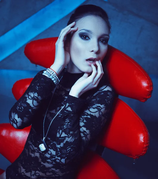 Modny model siedząc w fotelu na czerwony — Zdjęcie stockowe