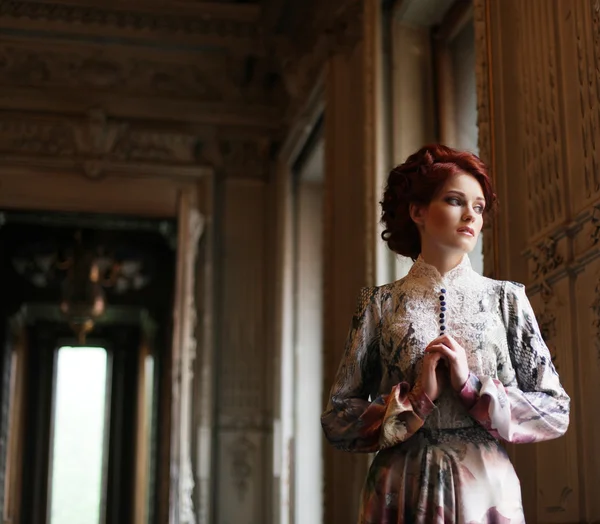 Mooie vrouw staat in de paleis kamer. — Stockfoto