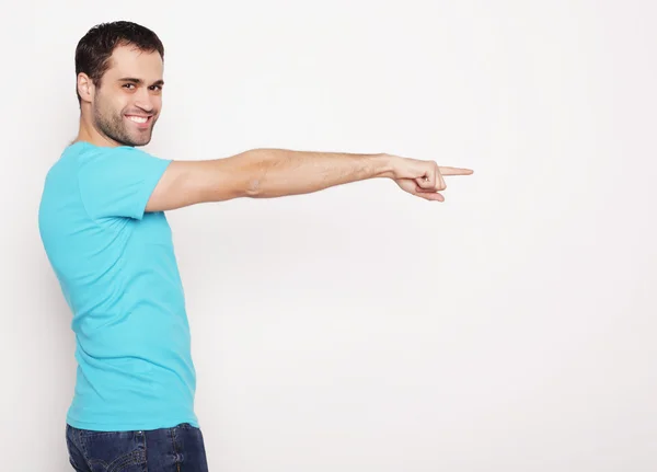 Joven sonriente feliz hombre muestra algo —  Fotos de Stock