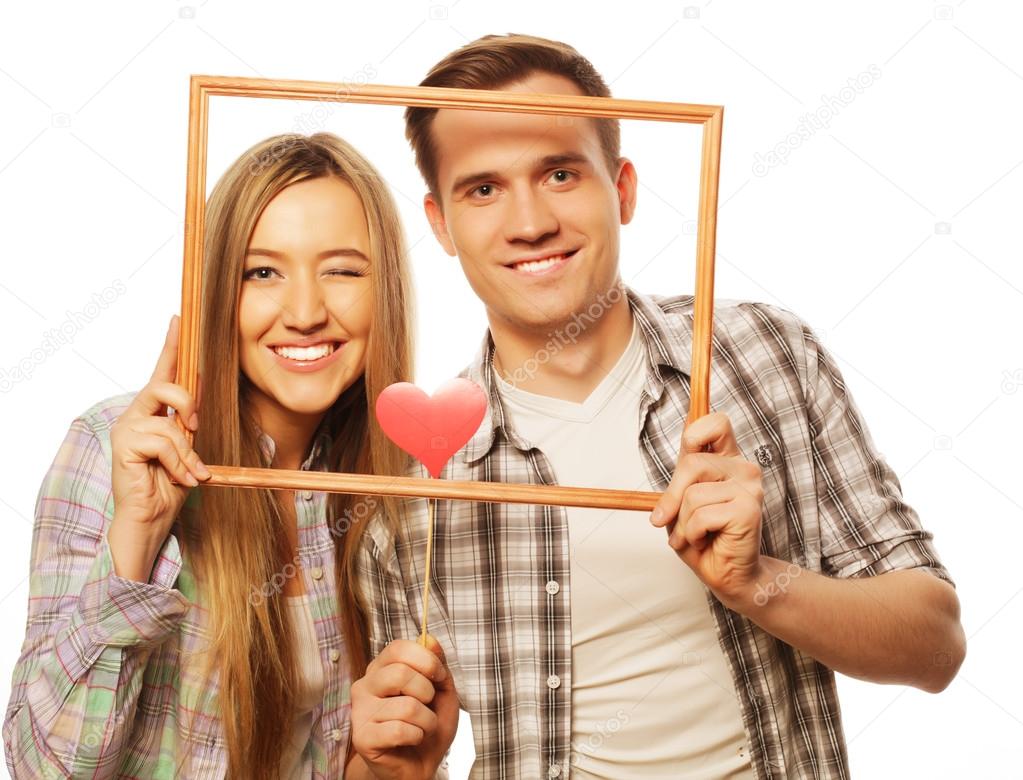 lovely couple holding frame and red hearts