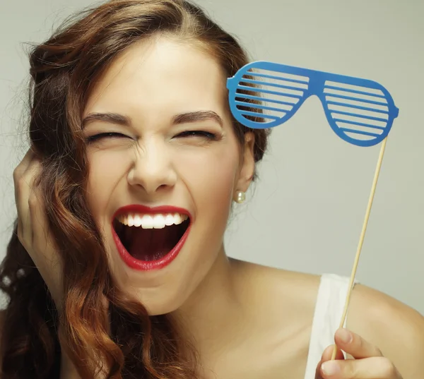 Jovencita juguetona sosteniendo unas gafas de fiesta . — Foto de Stock