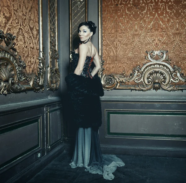 Junge schöne Frau steht im Palastzimmer — Stockfoto