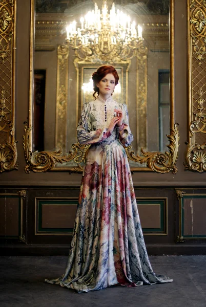 Vrouw staan in het paleis kamer met spiegel. — Stockfoto