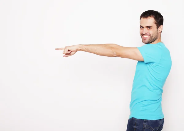 Young smiling happy man shows something — Stock Photo, Image