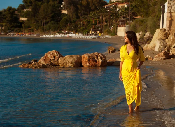 Frau mit gelbem Kleid am Strand. — Stockfoto