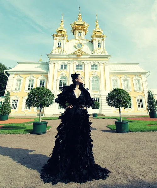 Mulher de vestido preto posando ao lado do palácio . — Fotografia de Stock