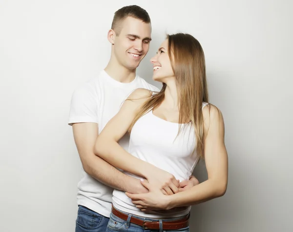 Schönes glückliches Paar, das sich vor grauem Hintergrund umarmt. — Stockfoto