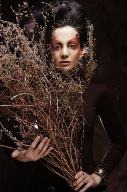 Kuru dallarla süslenmiş parlak bir kadın.