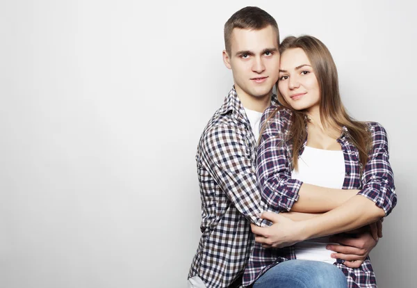 Encantadora pareja feliz abrazándose sobre fondo gris . — Foto de Stock