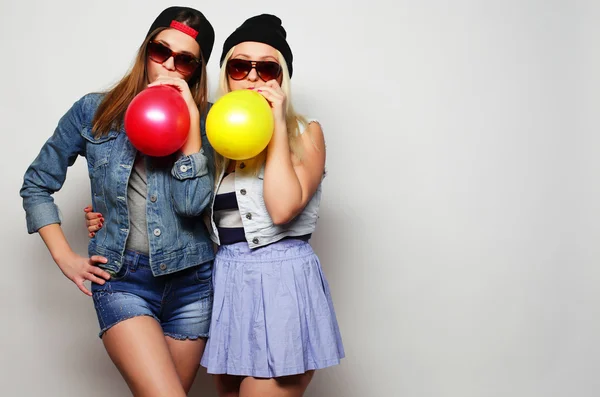 Chicas hipster sonriendo y sosteniendo globos de colores — Foto de Stock