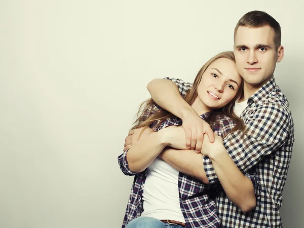 Encantadora pareja feliz abrazándose sobre fondo gris . — Foto de Stock