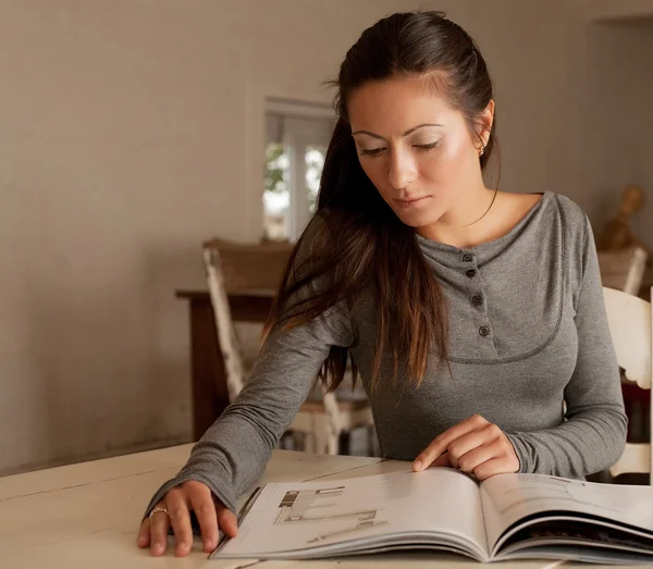 Jonge vrouw lezen tijdschrift thuis — Stockfoto