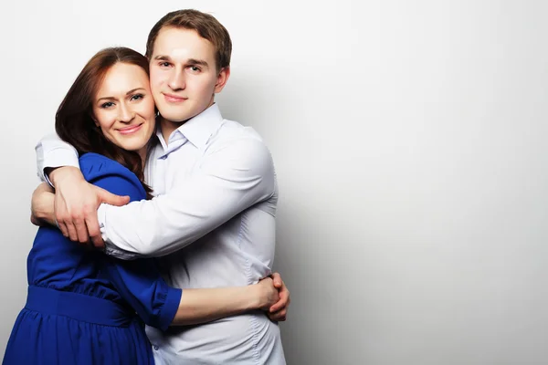 Encantador casal feliz abraçando sobre fundo cinza . — Fotografia de Stock