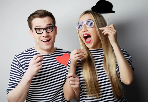 Pár drží party brýle a klobouk na tyčinky — Stock fotografie