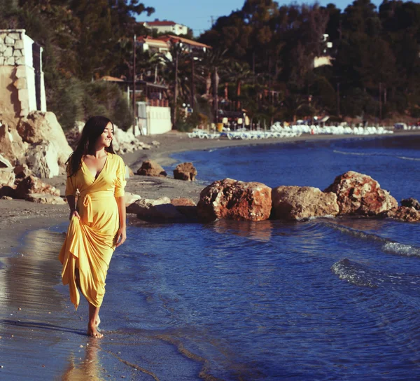 Frau mit gelbem Kleid am Strand. — Stockfoto