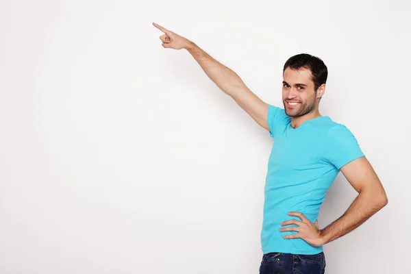 Joven sonriente feliz hombre muestra algo —  Fotos de Stock