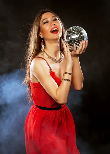 Jovem de vestido vermelho mantendo bola de discoteca — Fotografia de Stock