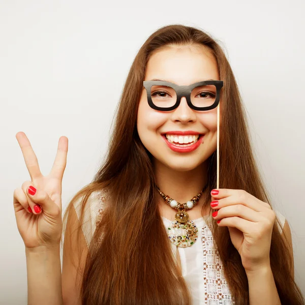 Mujeres jóvenes juguetonas sosteniendo unas gafas de fiesta . — Foto de Stock